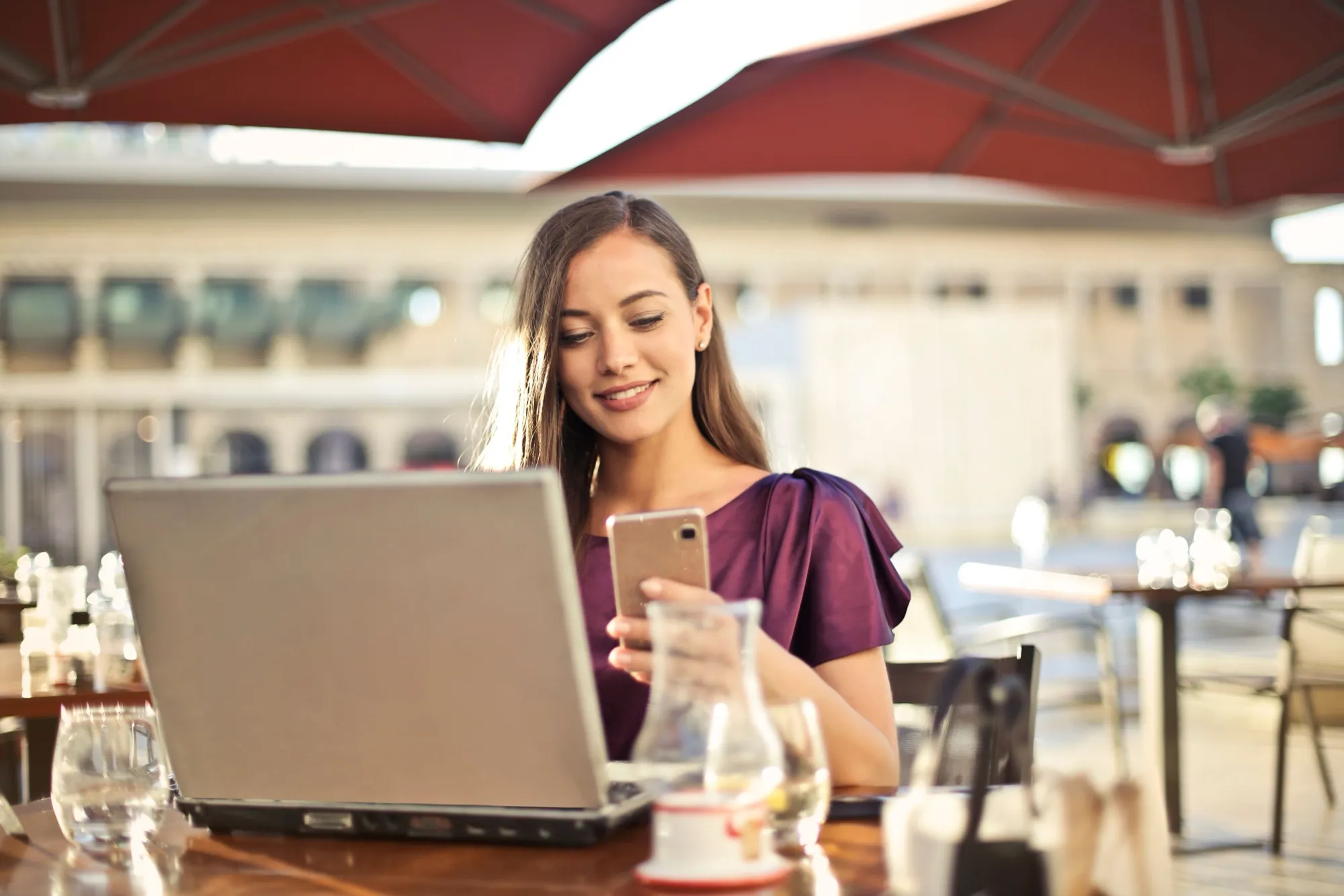 Selbstständige arbeitet im Café mit Laptop und Smartphone